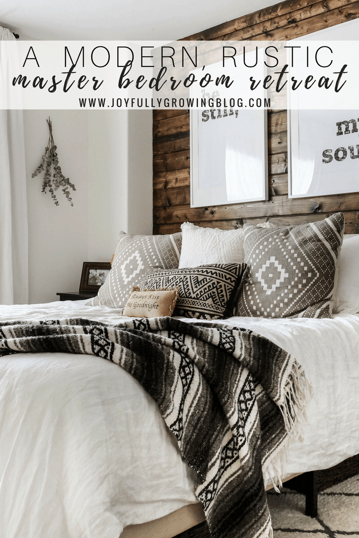 A rustic bedroom with a closeup of the bedding including throw pillows and blanket, up against a wood plank wall. Text overlay "A Modern, Rustic Master Bedroom Retreat - www.roomcursh.com"