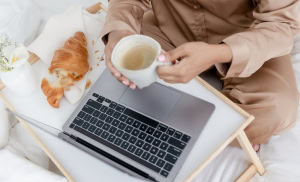 woman sips coffee typing Living On One Income budget tips that really work