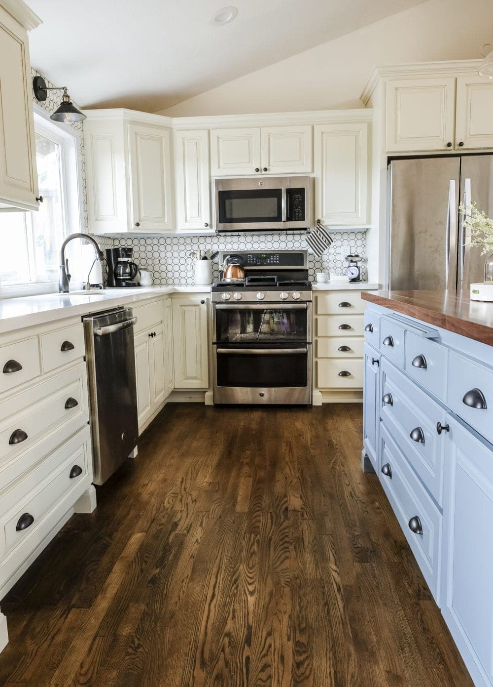 Kitchen with white cabinets and a blue kitchen island with farmhouse finshes and hardwood floors