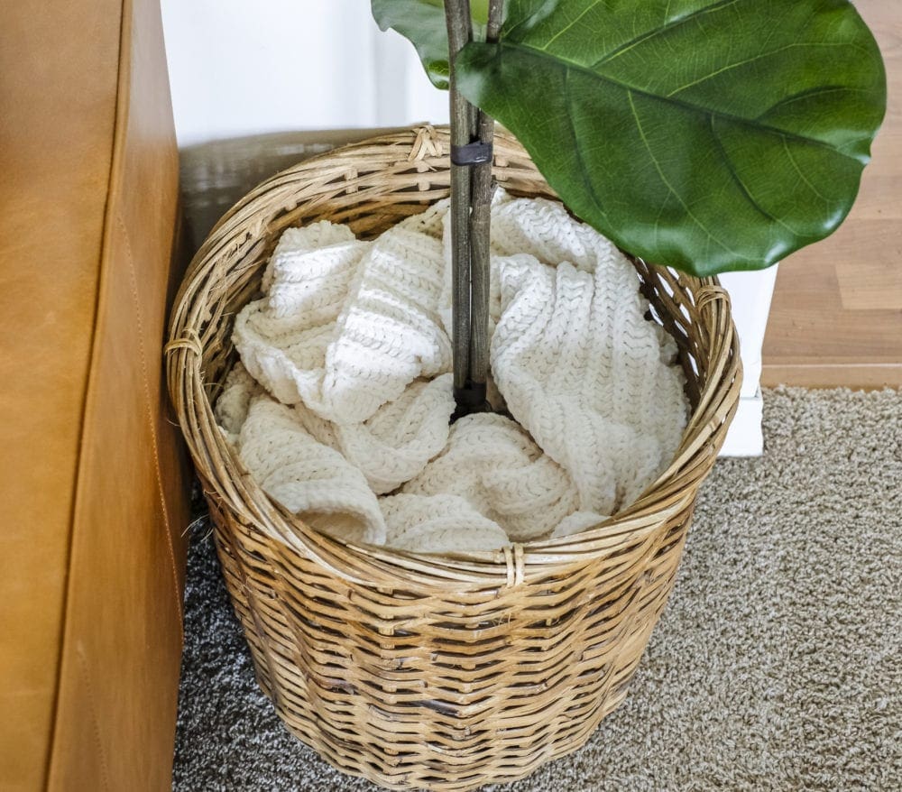 faux fiddle leaf fig tree sitting in a basket with a blanket covering