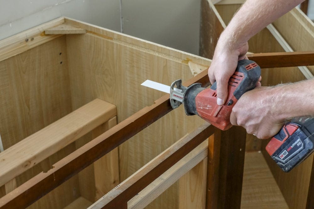 Cutting a cabinet with a sawsall starting to cut into cabinets to make room for farmhosue sink