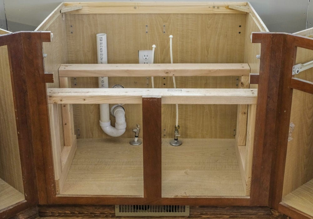 Cabinets with doors and countertops removed with the undersink cabinet cut into to make room for farmhouse sink