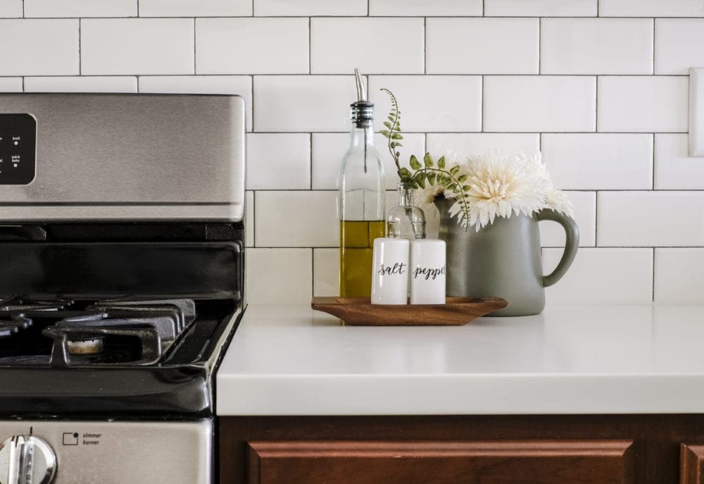 white countertops and subway tile decorated with salt and pepper shakers and olive oil dispenser 