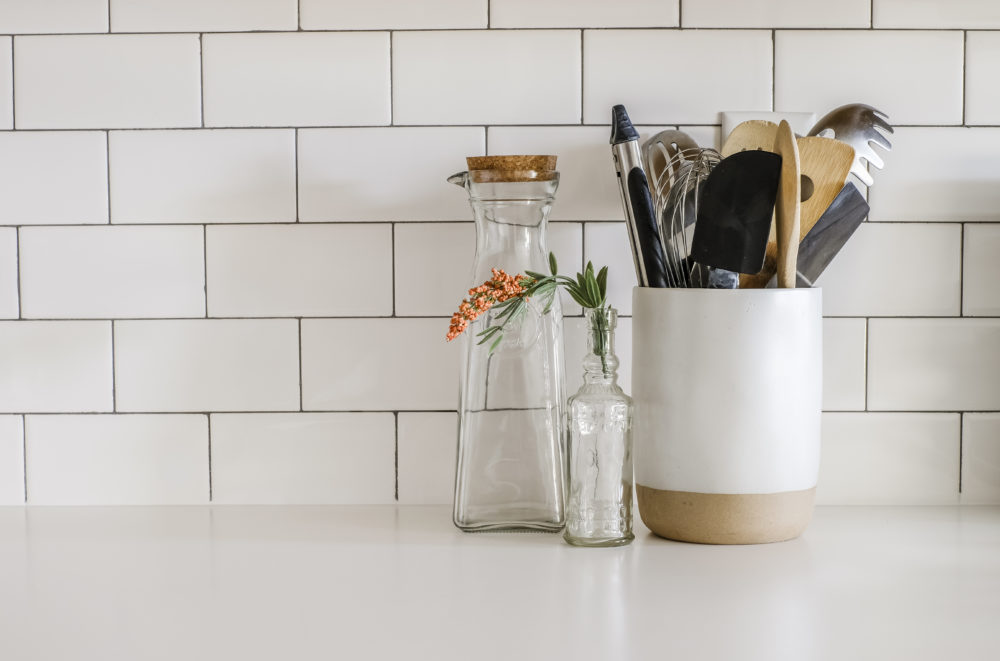 kitchen cooking utensils on white counter tops with white subway tile backsplash