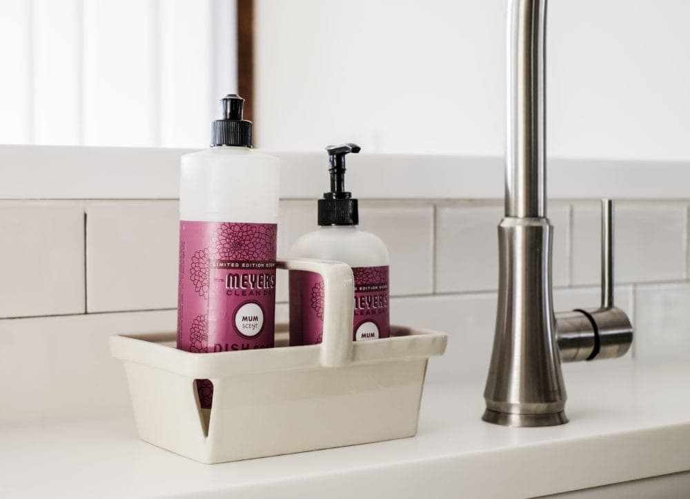 Meyers soap sitting on white solid surface counter tops in front of a subway tile backsplash