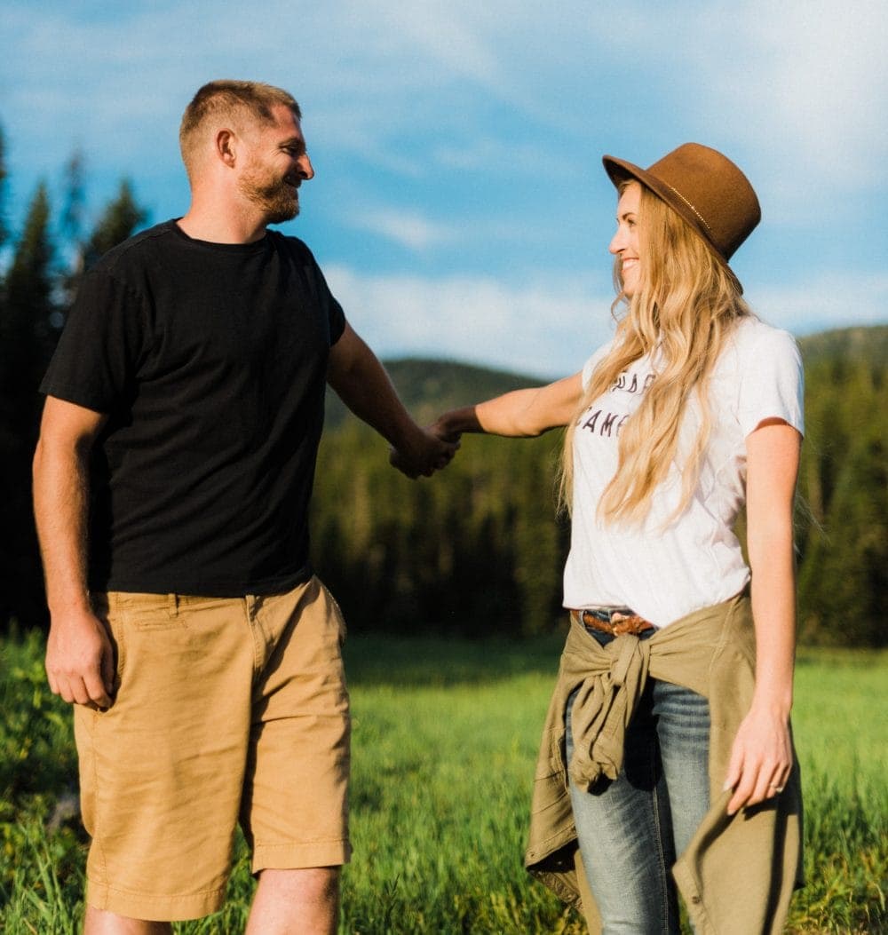 Blonde couple holding hands in the mountains during golden hour embracing RV life