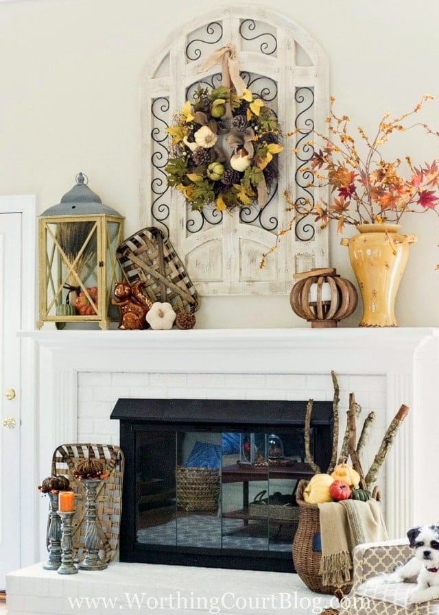 Fall mantel ideas using a basket of sticks, a lantern full of mini pumpkins and a cute fall wreath