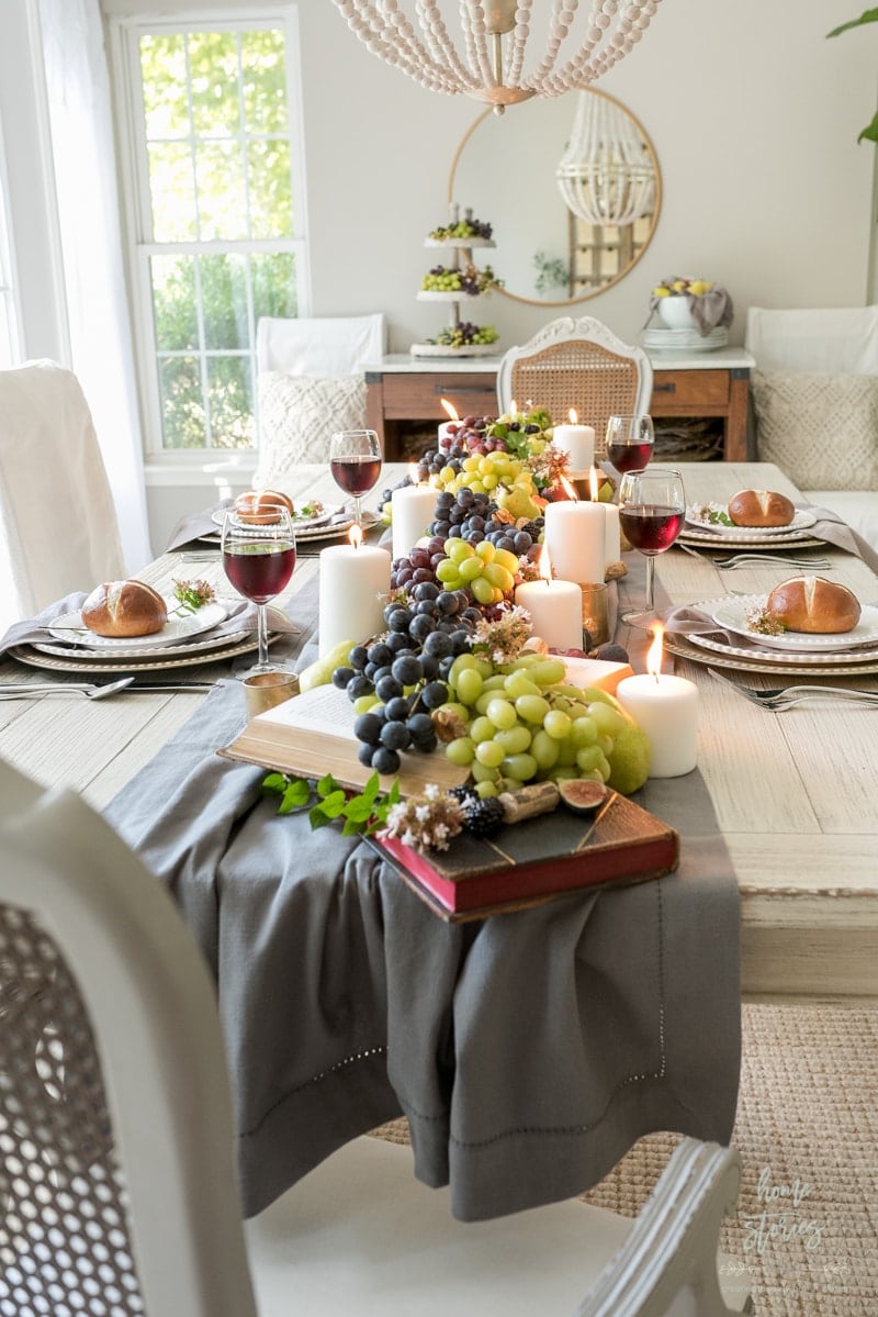 Thanksgiving table centerpieces with a grey runner, grapes and candles