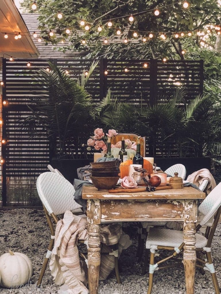 Thanksgiving table centerpiece on an outdoor table under string lights with moody colors and cozy knits