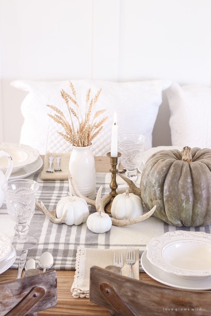 Thanksgiving table centerpieces with neutral colors using wheat stocks antlers and whit pumpkins