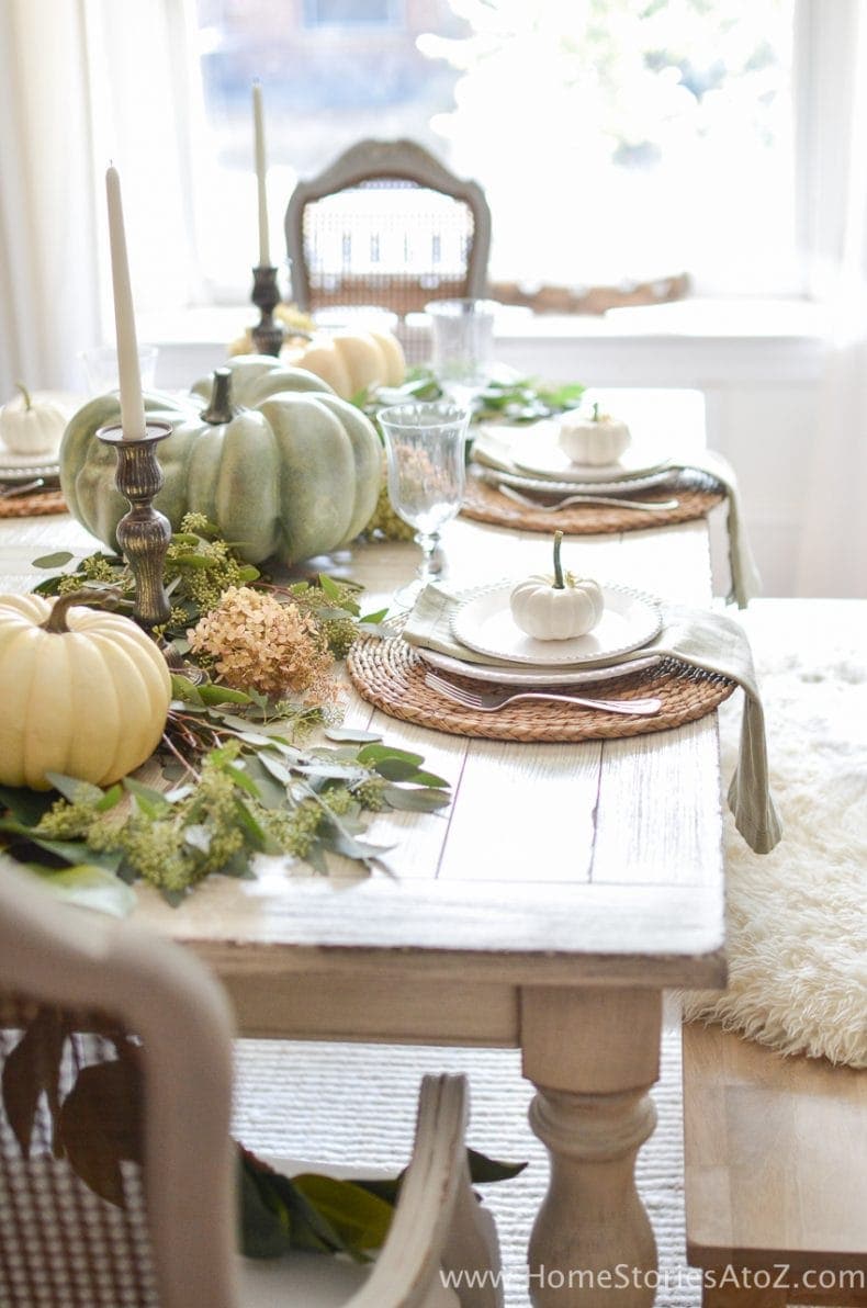 Thanksgiving table centerpieces with large gourds and round chargers