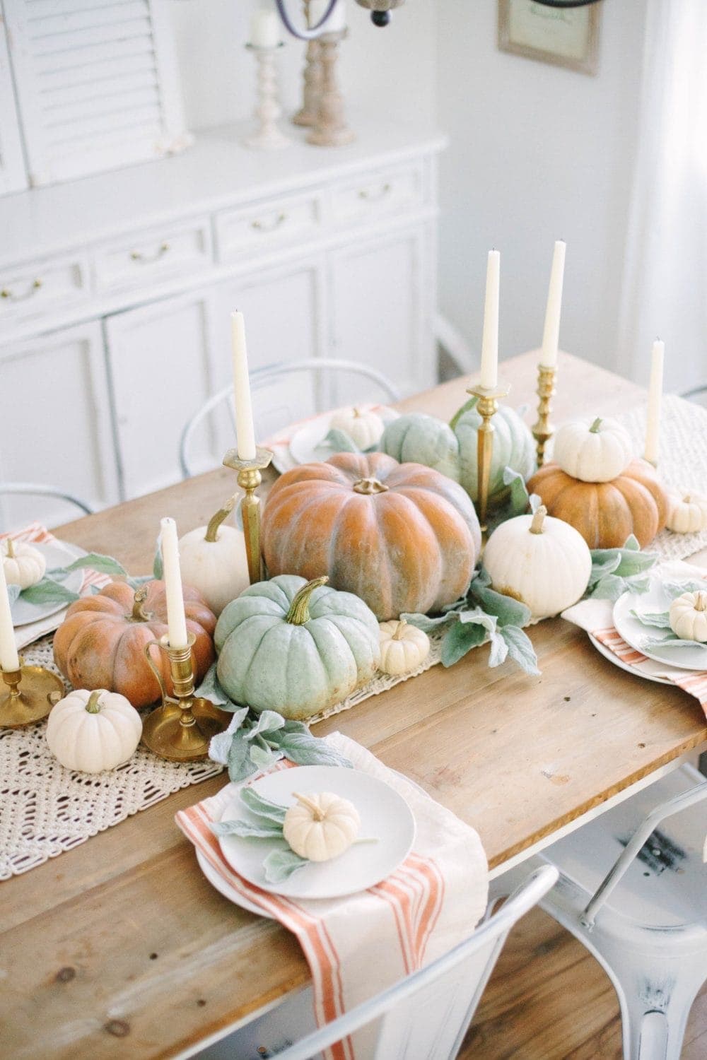 Thanksgiving table centerpieces with pastel colored pumpkins and vintage brass candlesticks