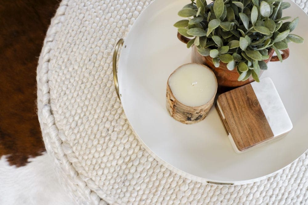 Overhead angle of a decorative tray that has a candle, greenery and coasters 