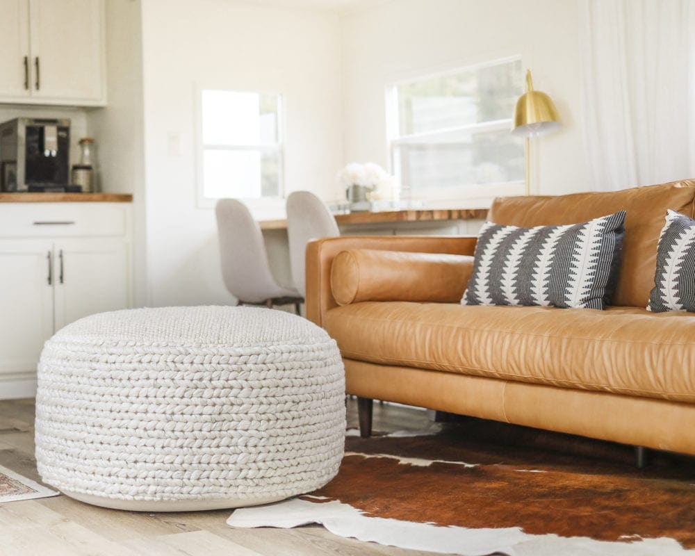 Large pouf for living room in front of a leather sofa