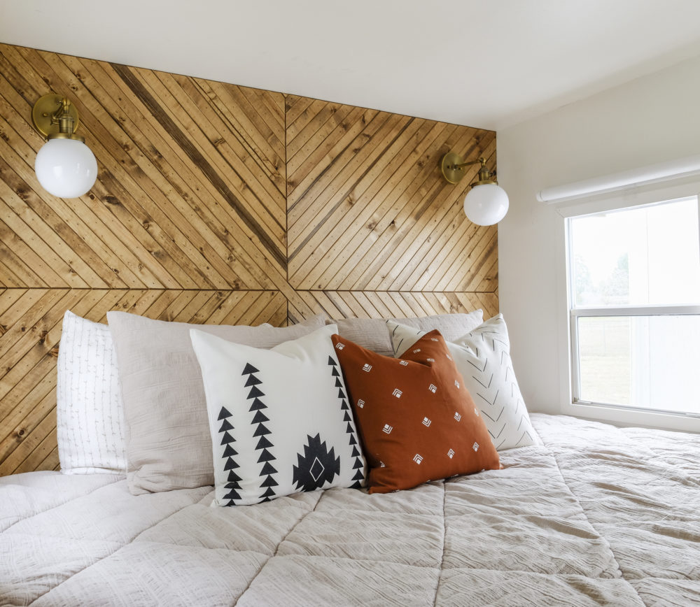 RV bedding and throw pillows in front of a wood accent wall