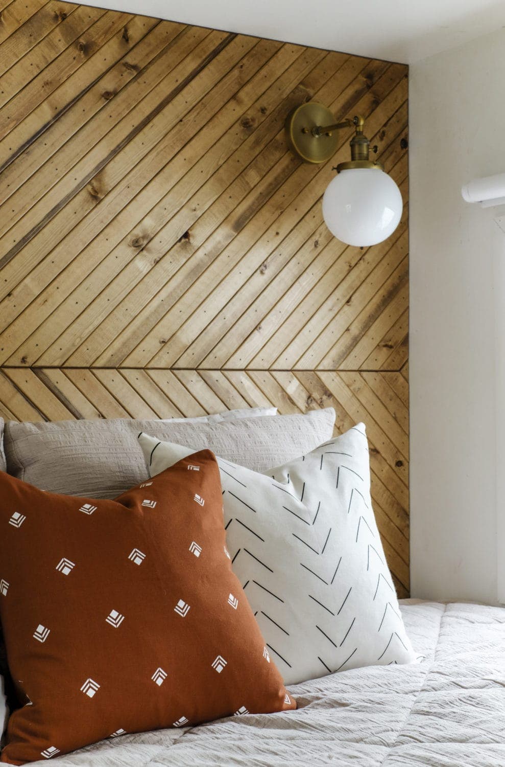 Closeup of geometric pillow covers in front of a wood accent wall