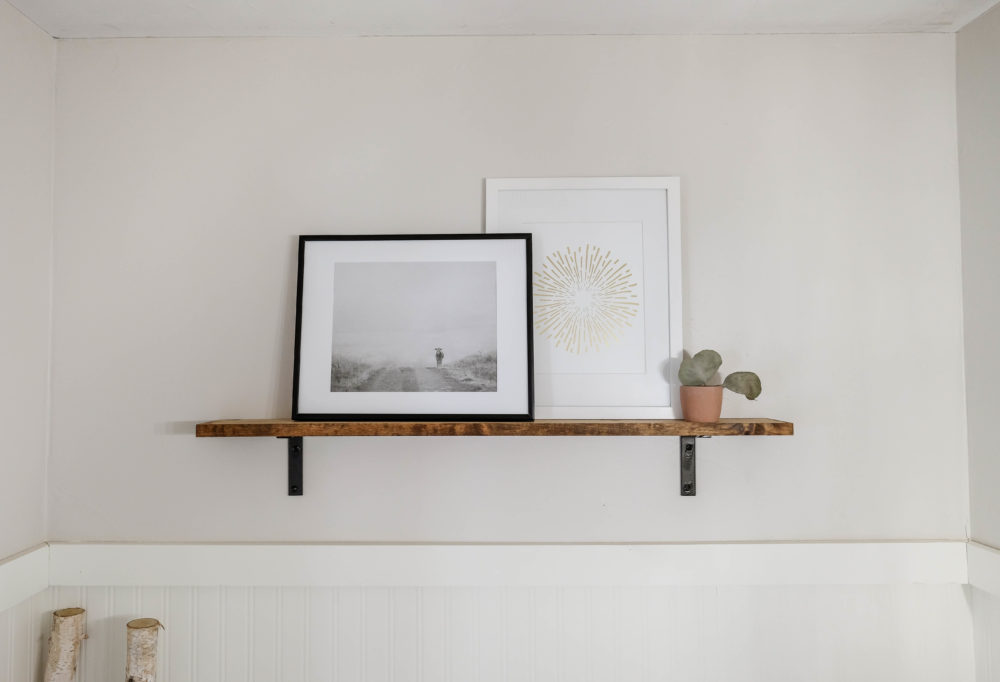 framed prints on an open shelf on a white wall