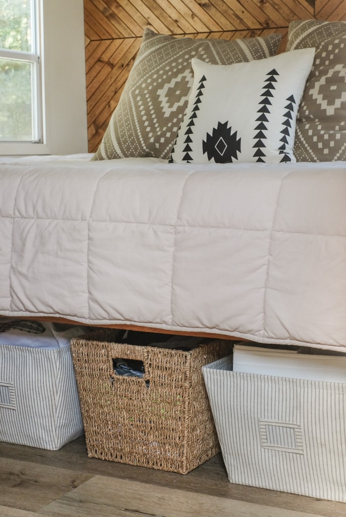 an organized bedroom with storage baskets under the bed