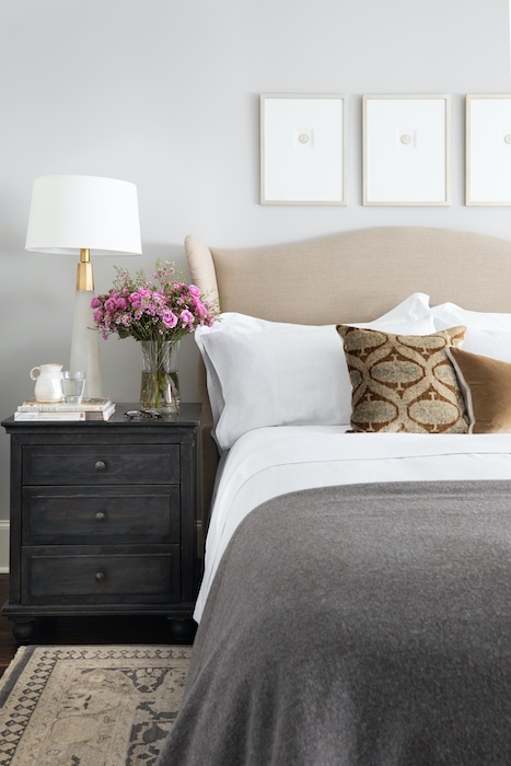 nightstand with a lamp and decor and a flower arrangement